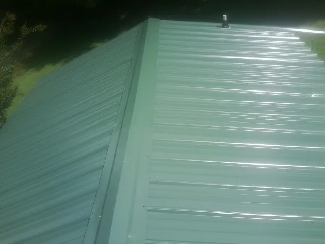 New green metal panels meeting at the ridge of a roof — Flat Roof Repair work by our crew in Greenfield Park