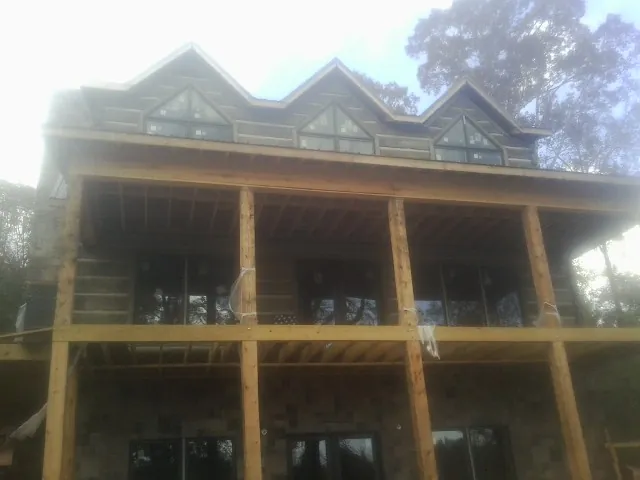 Dormers and porch framing on a large log home under construction — Roof Coating work by our crew in Greenfield Park