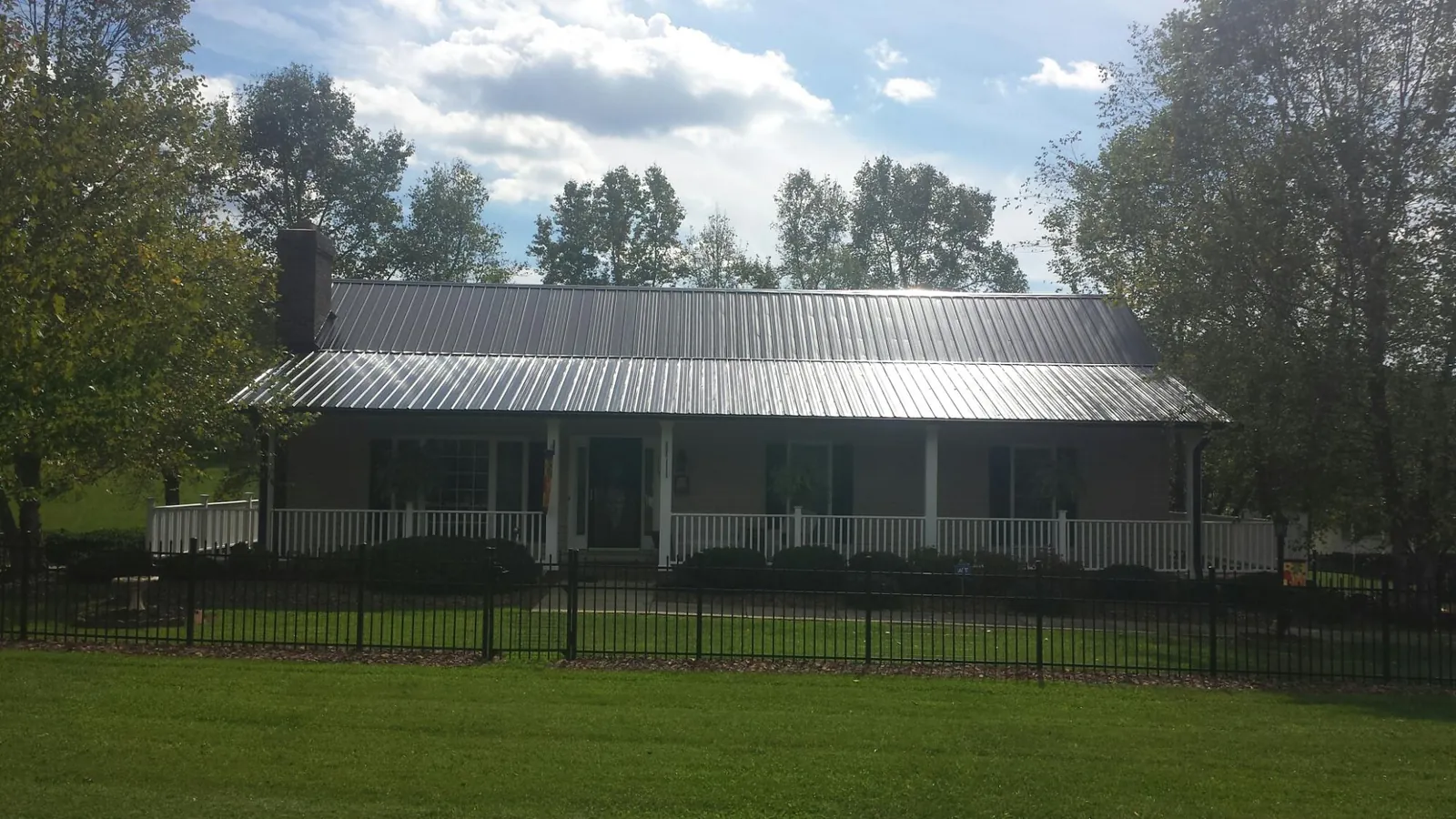 Gray metal roof on a brick ranch with a full width front porch — Gutter Guard Installation work by our crew in Greenfield Park