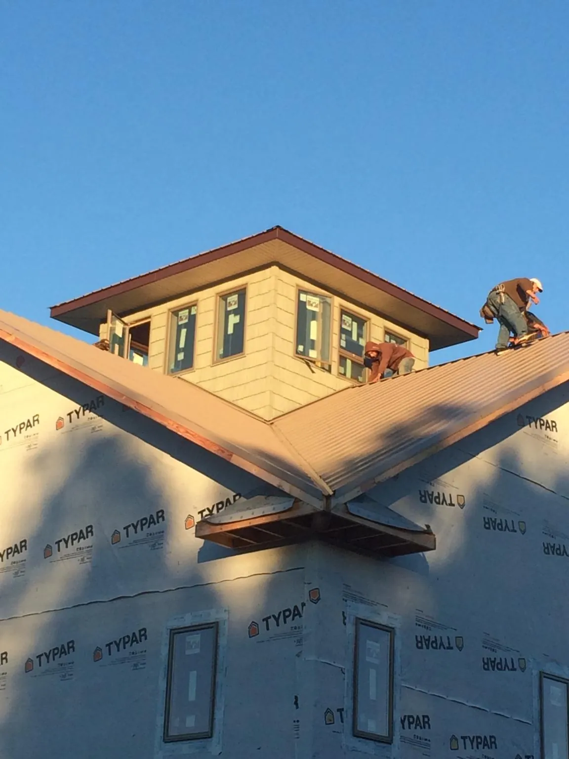 Roofers working around a rooftop cupola on a new metal roof at sunset — Roof Waterproofing in Greenfield Park by Roofing Brothers